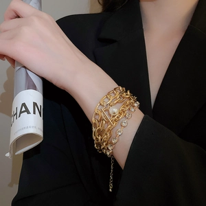Detail showing gold chain bracelets with white pearls and sparkling rhinestones