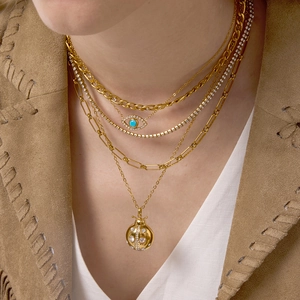 Détail de colliers superposés en acier doré avec pendentifs œil et coccinelle