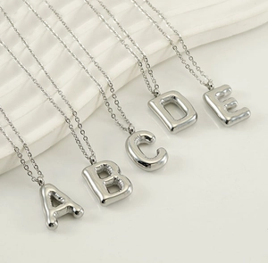 Macro shot of silver bubble initial necklaces A-E with rounded metallic luster on white