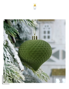 Detail of green flocked acorn ornament with honeycomb texture on snowy pine branch