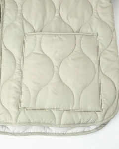 Detail of wavy quilted fabric on a beige cotton jacket with a large patch pocket
