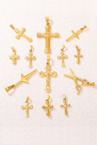 Flat lay of 12 golden stainless steel charms including crosses, daggers, and scissors