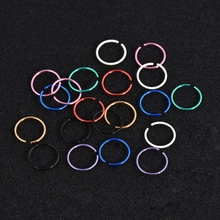Overhead view of colorful stainless steel lip and cartilage piercing rings on black texture