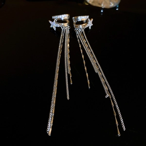 Dettaglio di orecchini a nappa in argento con zirconi a stella su sfondo nero