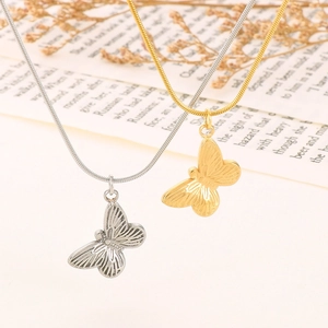 Macro shot of gold and silver butterfly pendants on snake chains over vintage pages