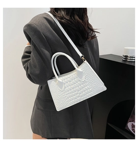 Detailansicht einer weißen Handtasche mit Krokodilprägung und elegantem Schultergurt-Design