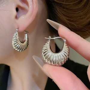 Macro detail of silver croissant hoop earrings showing spiral texture and polished finish
