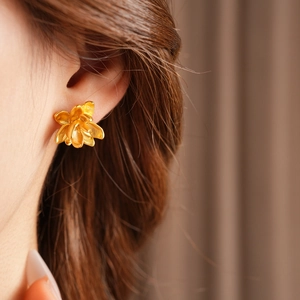 Detailopname van gouden lotus oorknopjes met elegante vintage metalen texturen