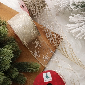 Champagne gold Christmas sheer ribbon with snowflake patterns and mesh texture on pine needles
