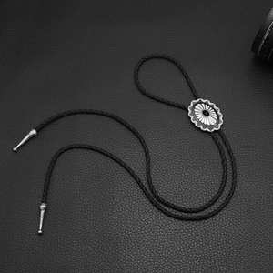 Silver Celtic floral Bolo Tie with black braided leather cord on a leather background