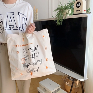 Detail view of canvas tote bag with artistic draw your every day print and handles