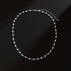 Detail of adjustable silver chain connection with round white pearls on black texture