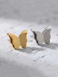Macro detail of 3D matte butterfly earrings with layered textures and metallic finish