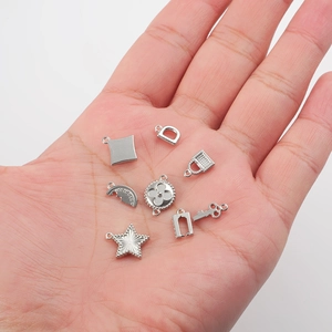 Seven silver stainless steel charms including star key and lock held in palm