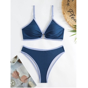 Flat lay of ribbed blue bikini set with purple trim, straw hat, and summer accessories