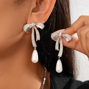 Boucles d'oreilles nœud argentées avec strass brillants et pendentifs perles gouttes