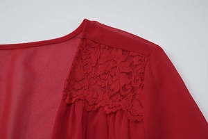 Détail en gros plan d'une robe en mousseline rouge avec dentelle raffinée sur l'épaule