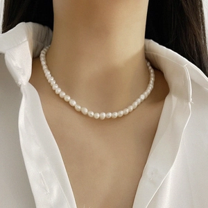 Close-up of baroque natural pearl necklace worn by a model on a white shirt