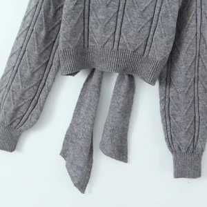 Detail view of grey cable knit sweater featuring V-texture and waist tie design