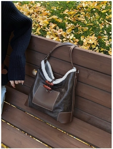 Detail of brown faux leather shoulder bag with white fleece trim and horn button closure