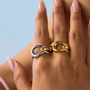 Close-up of minimalist U-shaped gold and silver tone rings worn on fingers