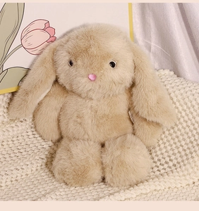 Close-up of beige plush rabbit doll with soft long fur on a white knitted blanket