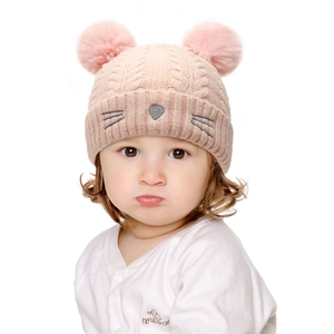 Detailed view of pink knitted baby hat with dual faux fur pom poms and cat embroidery