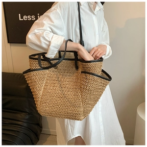 Detail of woven straw tote bag featuring black leather straps and large capacity