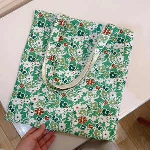 Detailed view of canvas tote bag featuring green floral pattern with dual handles