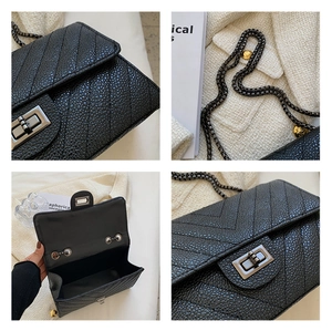 Detail of black lychee leather bag with V-shaped quilting and silver swivel lock