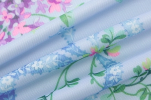 Close-up of light blue floral knit fabric with pink and purple flowers and soft texture