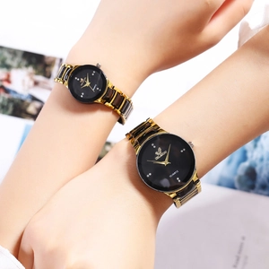 Detail shot of couple watches with gold steel straps and black diamond-studded dials
