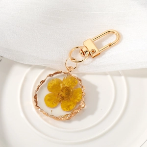 Detailed macro of a gold irregular resin pendant featuring a real yellow dried flower