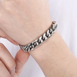 Close-up of a 12mm silver polished stainless steel Cuban link bracelet on a model wrist