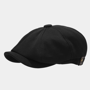 Detail view of black newsboy cap featuring breathable knit fabric and side leather strap