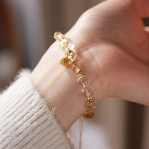 Detail of citrine and quartz beaded bracelet with gold lotus charm on a model's wrist