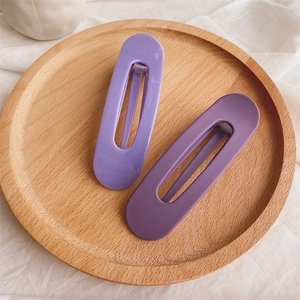 Detail of matte purple large hollow hair clips on a wooden tray with linen fabric