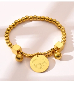 Detailed macro of gold-plated titanium bead bracelet featuring engraved eternal love disc
