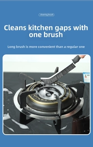 Detail showing stiff black bristles of a gap cleaning brush scrubbing a gas stove crevice