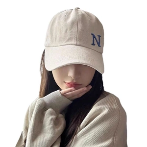 Beige cotton baseball cap with blue embroidered letter N worn by an Asian female model