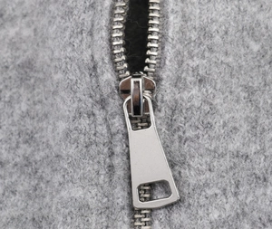 Detailed macro view of the sleek silver metal zipper on a grey knitted hoodie jacket