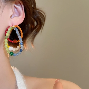 Close-up of vibrant colorful beaded hoop earrings on a model showing a luxury design