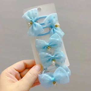 Close-up of light blue polka dot tulle bow hair ties with pearl pendants on display card