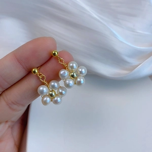 Detailed close-up of a flower-shaped natural freshwater pearl earring held in hand