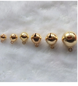 Detailed view of six gold-plated metal craft bells in various sizes on white plush background