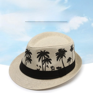 Detail of woven straw fedora hat featuring black palm tree silhouettes and ribbon