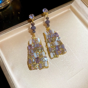 Detailed close-up of vintage gold drop earrings with purple beads and crystals