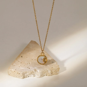 Detailed macro view of 18K gold plated moon shell pendant on elegant beige travertine