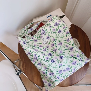 Dettaglio della borsa tote in cotone con stampa floreale viola su un tavolo di legno