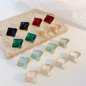 Square enamel stud earrings in multiple colors on textured stone display base